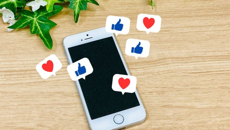 スマートフォンとSNSの“いいね”アイコンが浮かぶイメージ。人気ドラマの裏話や小ネタの拡散を連想させるビジュアル。