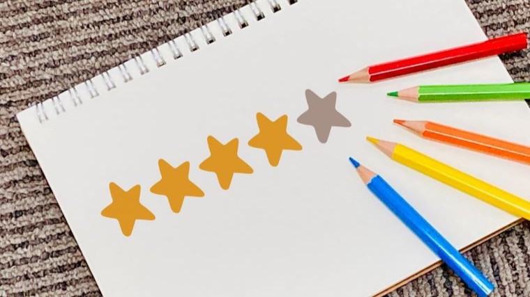 5段階評価の星マークと色鉛筆が描かれたノートの画像。レビューや評価を示すイメージ。