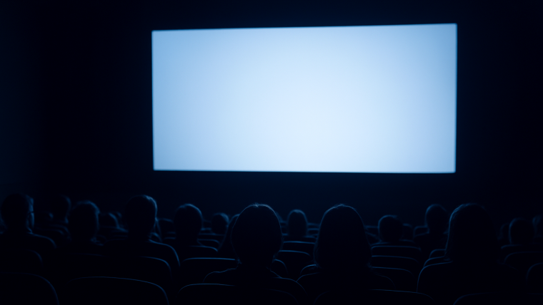 暗い映画館で観客がスクリーンを見つめる後ろ姿のシルエット。これから始まる物語への期待感を表すイメージ